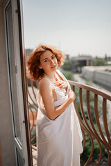 Redhead woman wrapped in sheet on balcony during daytime