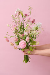 Delicate pastel flower bouquet held by hands against a soft pink background, perfect for spring themes or romantic visuals.