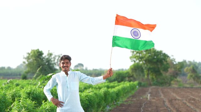 Young indian farmer waving indian flag at agriculture field 