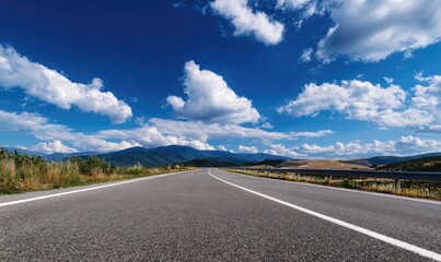 Fototapeta premium Open road stretches into a landscape of hills under a vibrant blue sky