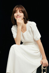 Smiling woman in white dress with elegant pose.