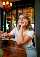 woman in cafe, happy middle-aged woman enjoying coffee alone at a cozy café