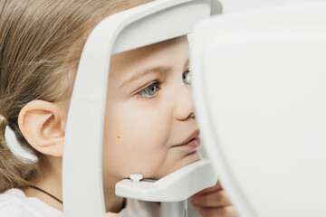 Child undergoing vision testing with advanced ophthalmic equipment, focused on eye examination...