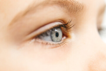 Close-up of a child's eye showcasing vibrant blue iris and long eyelashes, highlighting the...