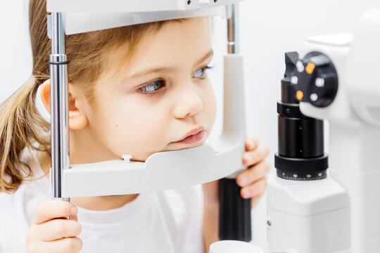 Young girl undergoing vision testing at an ophthalmology clinic, focused on the eye examination equipment, showcasing the importance of pediatric eye care and early vision assessment for children