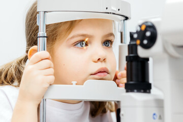 Young girl undergoing vision testing with advanced ophthalmic equipment, focused on the examination...