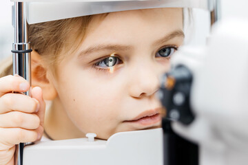 Young girl undergoing vision testing with ophthalmic equipment, focused on eye examination,...