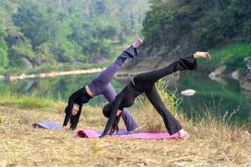 Asian Indonesian women doing yoga pose outdoors by the river in lush tropical nature