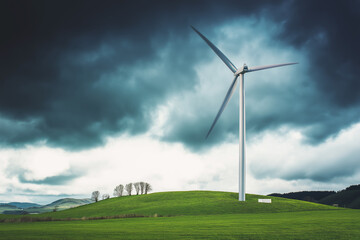 Obraz premium Wind turbine slowly rotating on a green hill, dramatic sky in background, clean landscape with minimal visual noise
