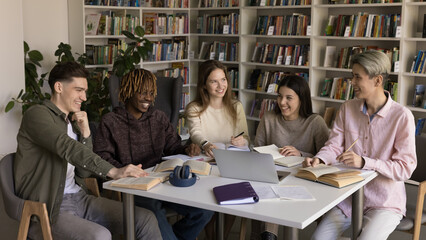 Collaborative education with fun. Diverse group happy university students from different ethnic backgrounds study together at library table smile discuss books share ideas on creative learning session