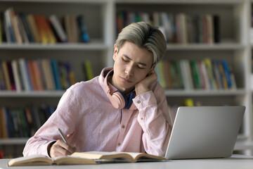 Deep in study. Serious busy zoomer male remote learning college student prepare assignment...