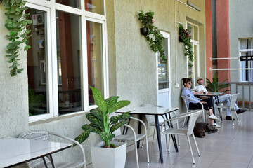 Young people sitting at a table in a street cafe with a dog