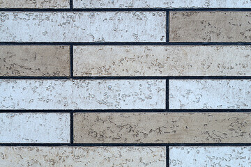 A fragment of a brick wall surface or a decorative imitation of a building facade. The colors of the masonry elements vary slightly from light to yellowish, apricot. Preset texture background.