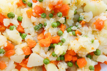 Mezcla cocida de patata, zanahoria y guisantes en plano detalle. Imagen colorida y casera, ideal para conceptos de comida real, recetas sencillas y cocina saludable.