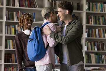Academic brotherhood and learning success. Two diverse young student guys groupmates share joyful supportive hug handshake with bonding laughter in classroom celebrate passing exam reunion after break