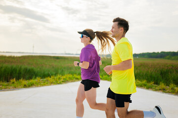 Joyful runners enjoying a summer jog along a scenic pathway at a lush lakeside park with scenic...