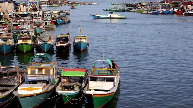 Traditional fishing activities using wooden boats on the Manggar River with a background of a row of boats anchored in the fishing village in the afternoon