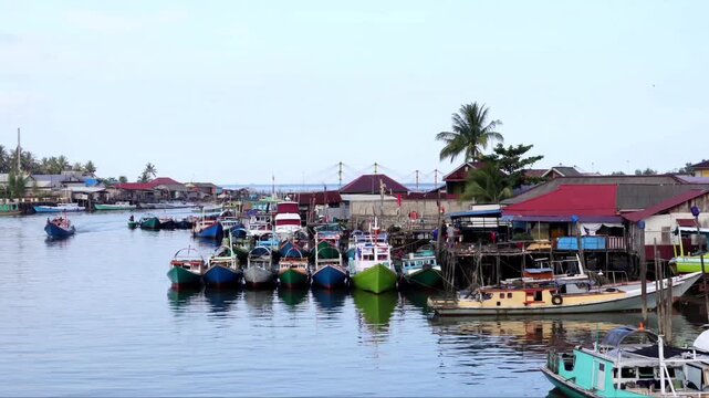 A row of traditional fishing boats lined up neatly in the Manggar fishing village in the afternoon with a calm atmosphere