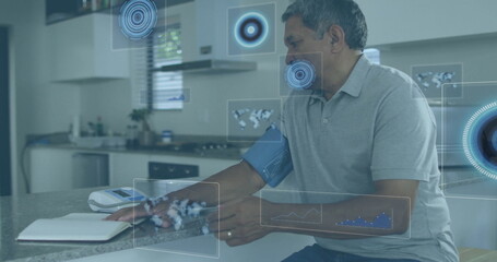 Elderly Hispanic man measuring blood pressure at kitchen counter, with digital cuff, copy space