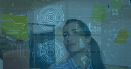 Data analyst in striped top combining sticky notes and digital charts in office, with planning