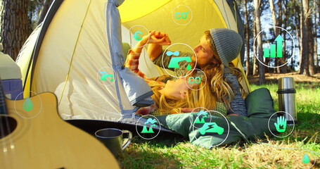 Sharing fruit slice, couple lying at yellow dome tent in forest clearing, with guitar, mug, thermos