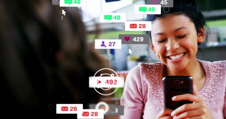 Smiling female holding smartphone and viewing floating social media icons at café, copy space