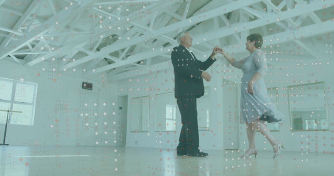 Dancing senior couple wearing suit and blue dress in dance studio, with hardwood floor and mirrors - Powered by Adobe