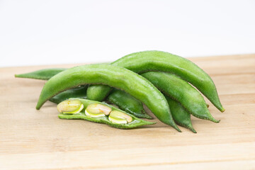 Close up of a wooden crate filled with broad beans,the green bean on background