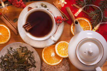 A cozy composition with aromatic tea, cinnamon, orange, rowan and New Year's garland, symbolizing festive warmth and winter atmosphere © Максим Новосветлов