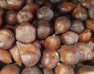 A fresh pile of exotic Salak, also known as snake fruit, showcasing its unique brown scaly skin texture.