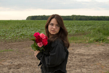A young attractive woman wearin eyeglasses holding a bouquet of roses	