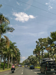A scenic drive down a wide, palm tree-lined boulevard on a sunny day with blue skies and light traffic