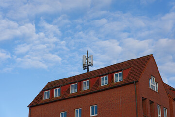 Red brick apartment building with roof antenna Broadcasting UMTS LTE WLAN 5G 6G Mobile Data
