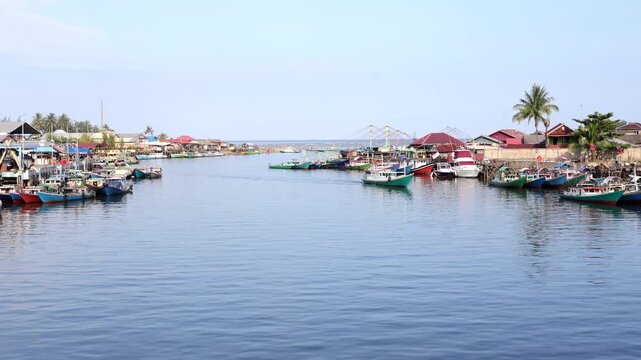 Traditional fishing activities using wooden boats on the Manggar River with a background of a row of boats anchored in the fishing village in the afternoon