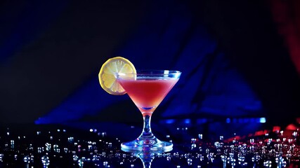 slow motion cinematic footage of a vividly lit cocktail glass with lemon surrounded by dual toned lighting water splashes and colorful reflections perfect for nightlife and drink advertisement - Powered by Adobe