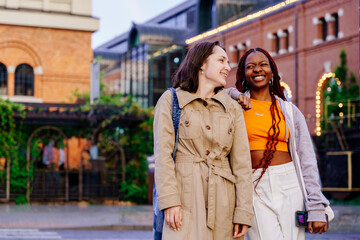 Fototapeta premium Diverse friends walk together talking and smiling after rain