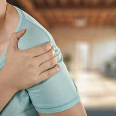Hands holding painful arm, fitness area background. Sport workout, stretching and joint health,...