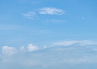 White, wispy clouds in a bright blue sky over a stunning sea
