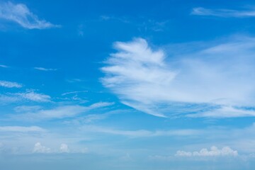 White, wispy clouds in a bright blue sky over a stunning sea