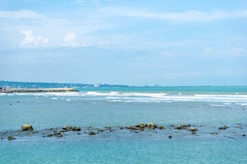 Vibrant blue ocean with striking rocky outcrops under a clear daytime sky in Tuban, Indonesia.