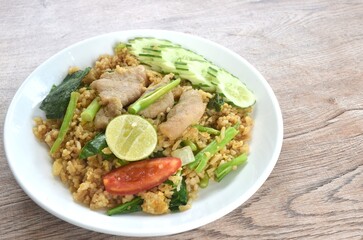 fried rice solf fermenting pork in black sweet soy sauce with slice cucumber couple lemon on plate 
