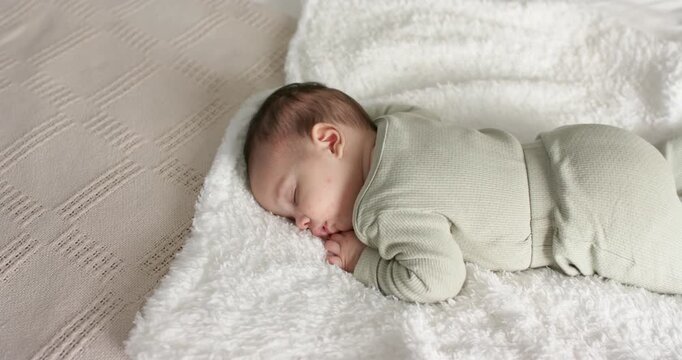At scene start, newborn infant is lying on white fluffy blanket and breathing gently to rest