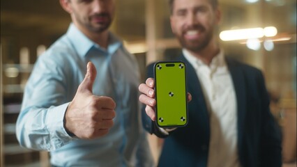 Caucasian men using mobile phone in office business app co-workers male guys smiling businessmen holding smartphone chroma key green screen mockup copy space online banking shopping recommend thumb up