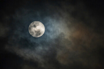 full moon in the midnight behind the cloudy sky