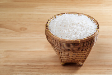 raw Thai's jasmine rice in Thai's traditional style bamboo's bowl on wooden dinner table
