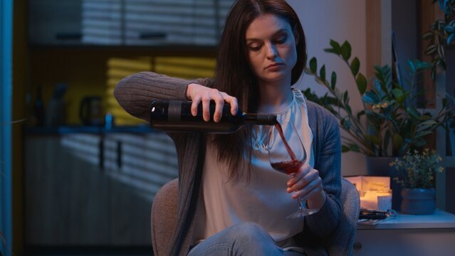 Woman opening bottle of red wine at home night drink alcohol relaxing in evening apartment single elegant girl Caucasian female rest alone tired suffer breakup drinking beverage addiction alcoholism - Powered by Adobe
