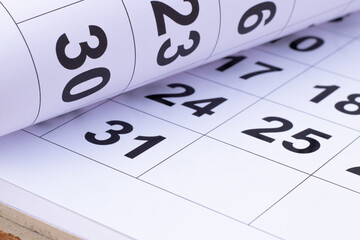 Paper rolled on the wooden table pointing number 30 in the calendar