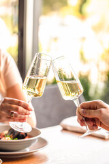 Two people toast with glasses of champagne in a bright and elegant dining setting. copy space