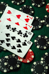 A collection of playing cards, including hearts and clubs, is displayed on a green felt table...