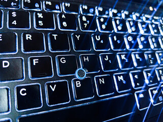 Backlit laptop keyboard with glowing illuminated keys in the dark
